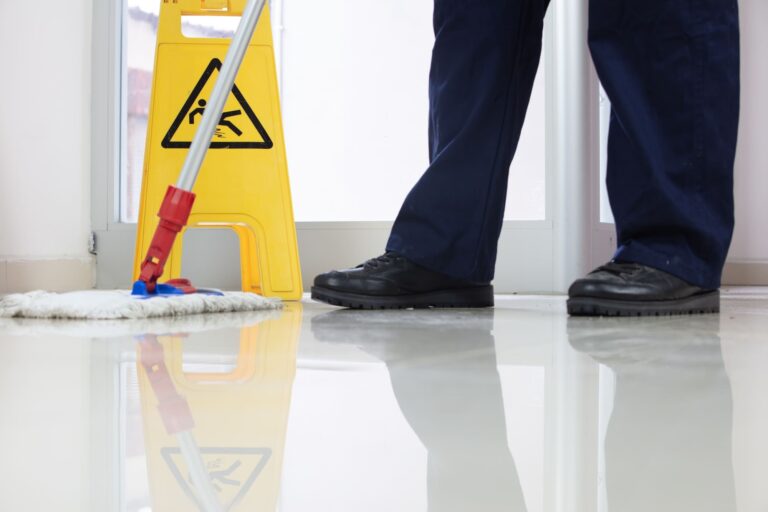low-angle-closeup-person-cleaning-floor-with-mop-near-yellow-caution-wet-floor-sign