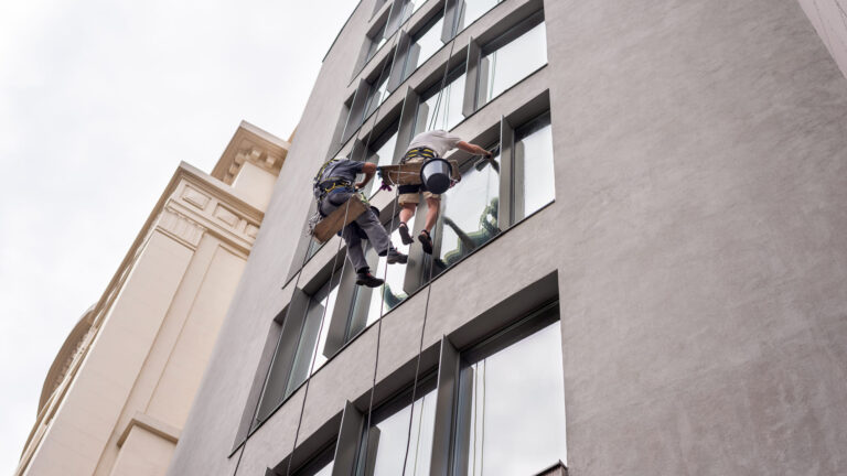 two-workers-washing-windows-outside-building